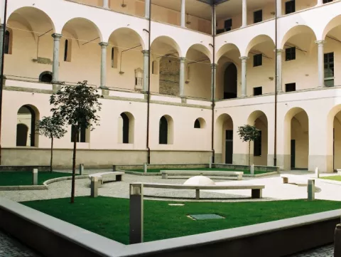 Cloister with arches, lawn, benches