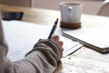 Picture of a student writing on a notebook