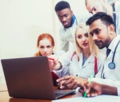 Postgraduates in medicine around a computer