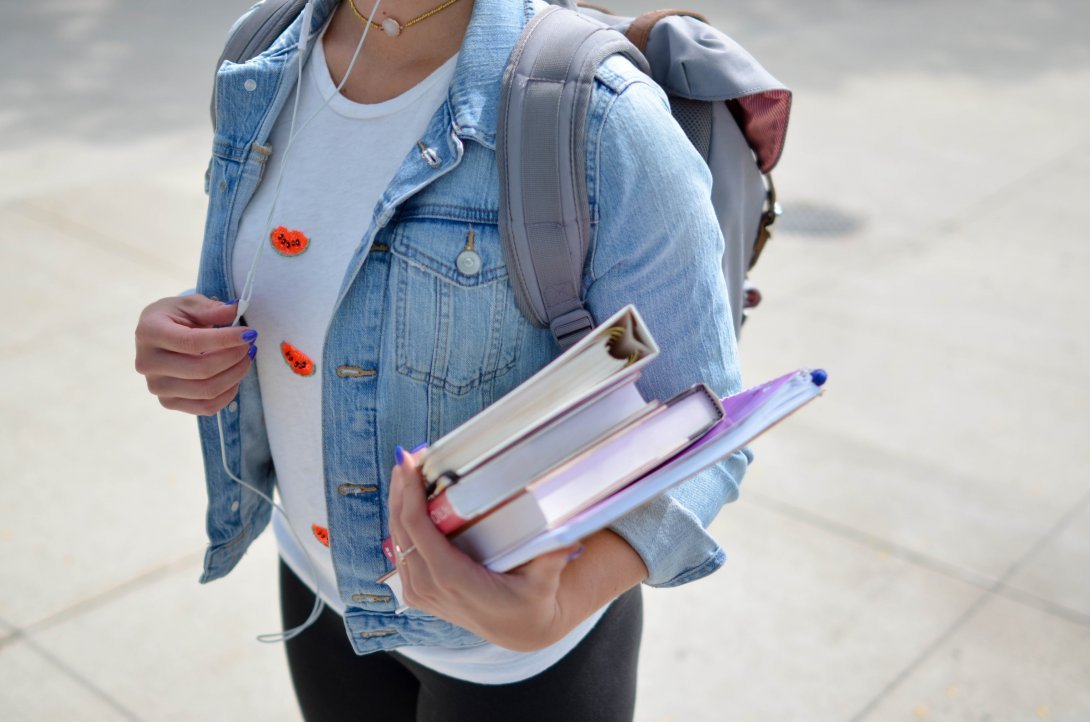 Image of a girl with a backpack, holding books