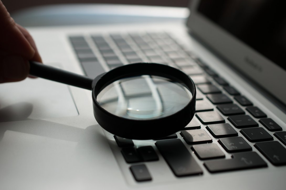 A photo of a magnifying glass resting on a computer keyboard
