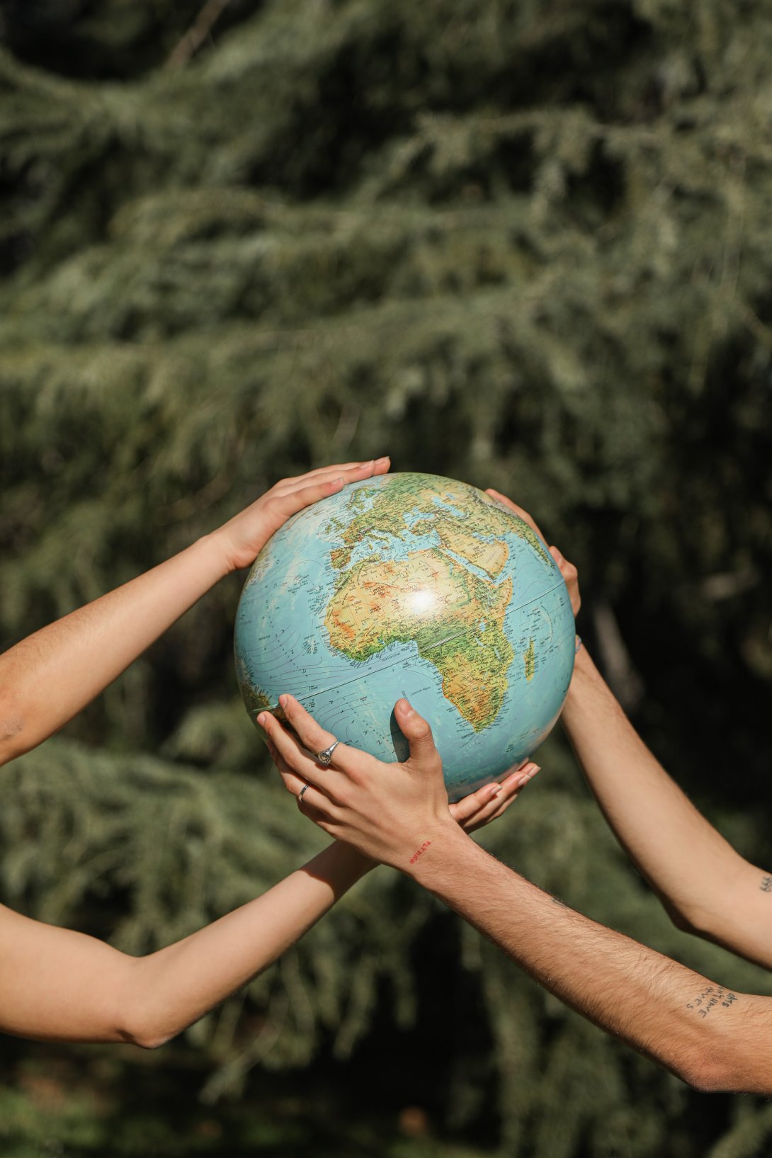 A photo of two hands holding a globe, a symbol of environmentalism and social cooperation