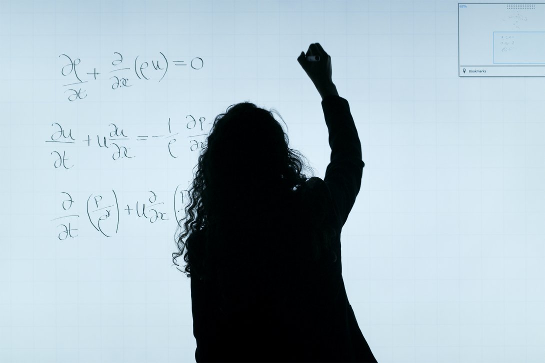 Photo of a woman writing on a blackboard 