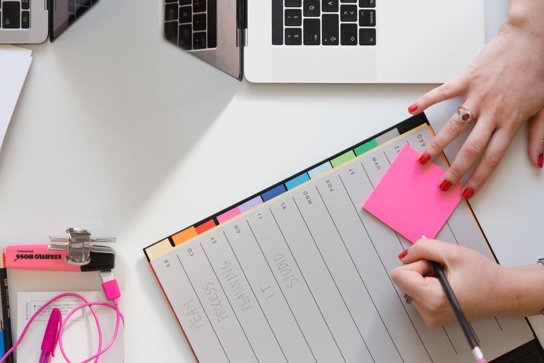 A photo showing a person's hands writing in a planner